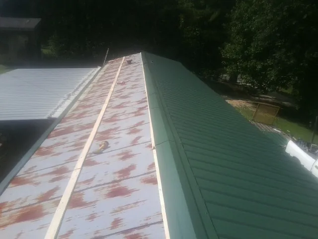 Old rusted panels beside newly installed green metal roofing — Wind Damage Roof Repair by Roofing Brothers in West Hempstead