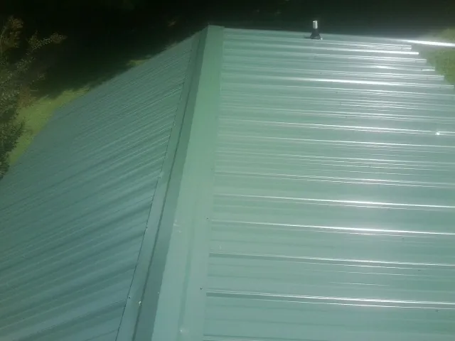 New green metal panels meeting at the ridge of a roof — Flat Roof Repair work by our crew in West Hempstead