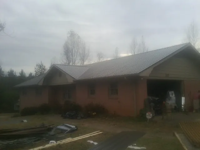 Gray metal roof on a stucco house with an attached garage in West Hempstead
