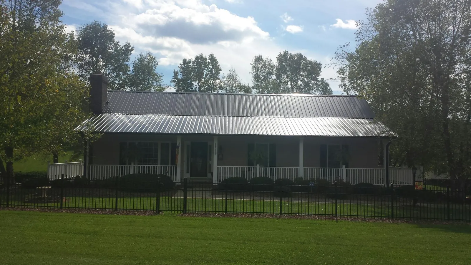 Gray metal roof on a brick ranch with a full width front porch — Gutter Guard Installation work by our crew in West Hempstead