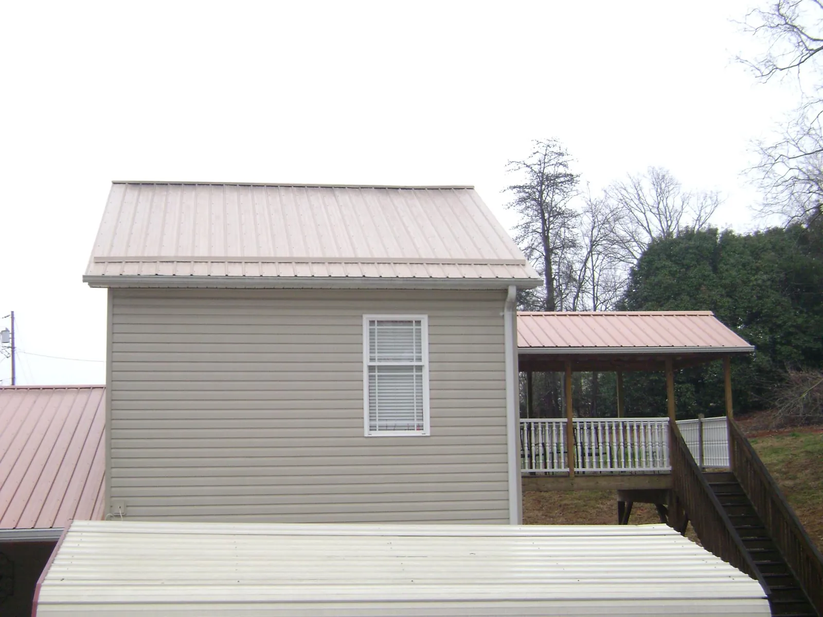 Tan metal roofs on a two story addition and attached porch, from a Roof Replacement job in West Hempstead